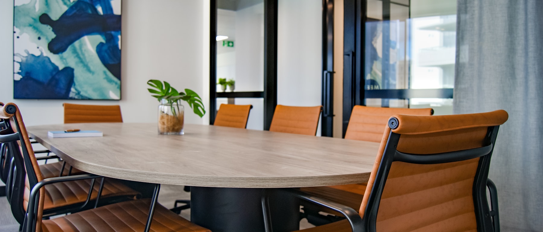 An empty boardroom with a long wooden table and chairs